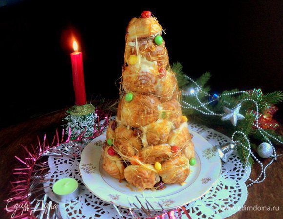 Осторожно снять бумажный конус и установить торт из профитролей на блюдо. Две вилки соединить спинками, окунуть в горячую карамель и разъединяя и соединяя вилки, вытянуть карамельные нити, обматывая ими крокенбуш. Дополнительно можно прикрепить на торт с помощью карамели разноцветные конфетки ММ. С Новым Годом и приятного аппетита!