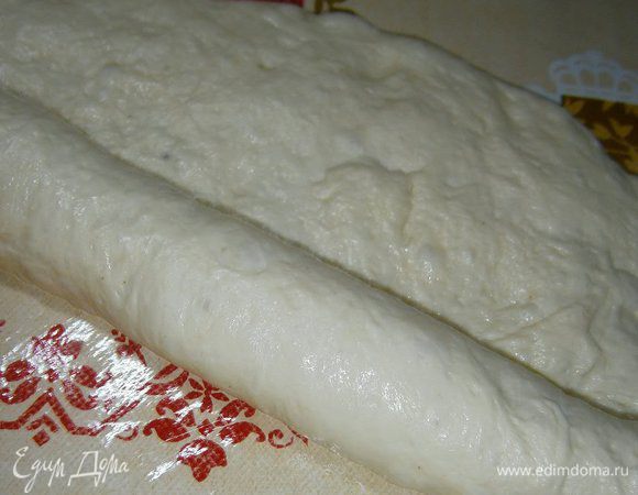 Подошедшее тесто обмять и разделить на несколько частей (у меня получилось 2 хлеба и несколько булочек). 
Кусок теста растянуть руками, свернуть рулетом...