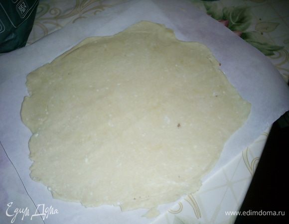 Раскатываем тесто прямо на бумаге для выпечки. Для удобства я рекомендую либо раскатывать через бумагу, либо же немного припудрить тесто мукой. Сразу же к раскатанному коржу прикладываем крышку, тарелку или дно формы для выпечки нужного диаметра и ножом вырезаем круг. Я выпекала 8 коржей диаметром 23 см. Обрезки собрала и раскатала чуть меньший 9 корж. Он нам будет нужен для посыпки.