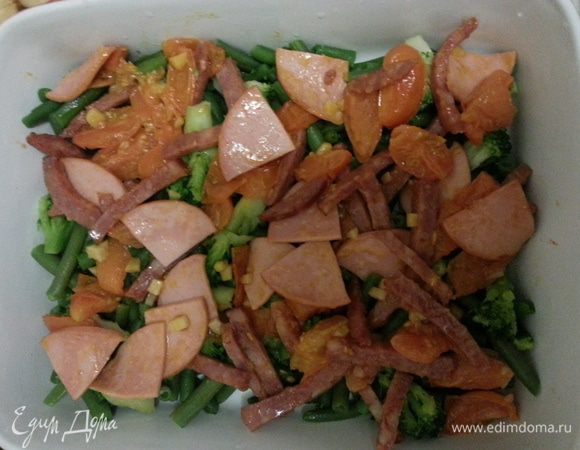 Нарезаем черри на 4 части, тушим на рафинированном масле, добавляем колбаску и мелко порезанный чеснок. Выкладываем в форму вторым слоем.