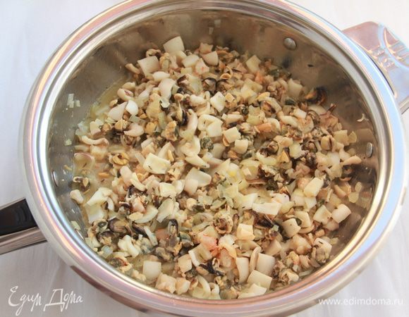 Добавить морепродукты и обжаривать ещё несколько минут.
Добавить муку, затем постепенно влить вино.