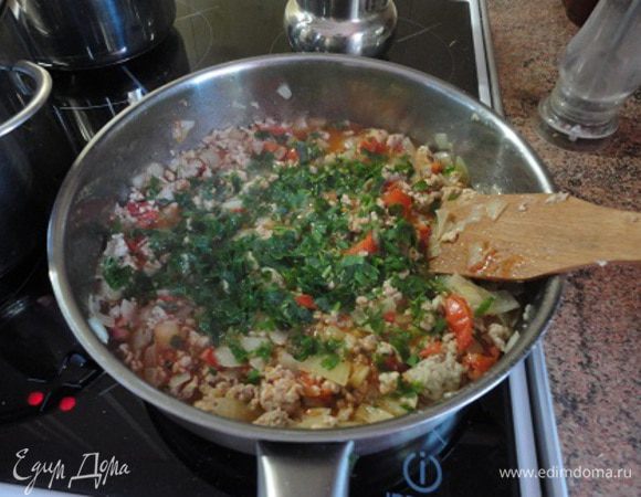 Приготовьте начинку: поставьте на небольшой огонь большую сковородку и разогрейте масло. Томите лук и чеснок до мягкости. Добавьте фарш и разомните так, чтобы не было комков. Обдайте помидоры кипятком, снимите кожицу, мелко нарежьте и положите к фаршу. Добавьте томатный соус. Посолите, поперчите и добавьте свежую зелень петрушки.