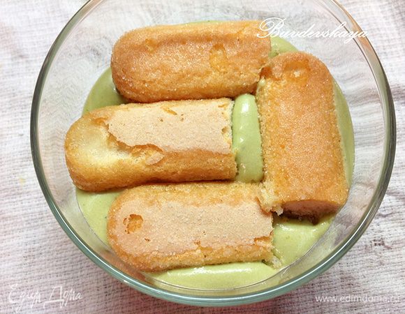 Печенье Савоярди по одному обмакните в сироп (по необходимости разрежьте на кусочки) и выложите на слой крема.