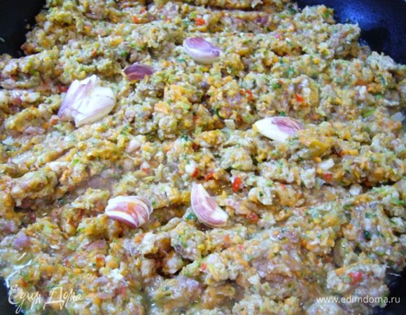 Разогреть сковороду, влить в нее оливковое масло. Как только масло нагреется, отправить в сковороду фарш. Даем немного ингредиентам «сговориться», периодически помешивая. Раздавить 4 неочищенных зубчика чеснока, отправить на сковороду к фаршу.