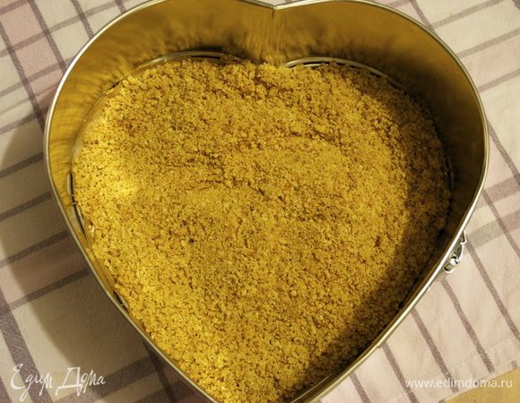 Выложить полученную влажную крошку в форму и разровнять по дну формы... Я на дно кладу пекарскую бумагу, так как в последствии проще доставать чизкейк из формы. Запекать в заранее разогретой духовке 10-12 минут, пока "корж" не приобретет золотистый оттенок. 