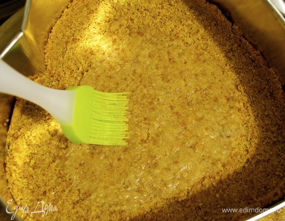 Яичный белок взбить слегка вилкой. Форму с готовым основанием для чизкейка достать из духовки и смазать взбитым белком. Дать остыть.  