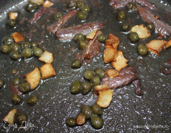 Добавить каперсы и филе анчоусов, разрезанное на 2 части. Жарить еще 1 минуту.