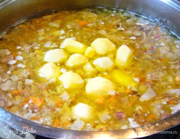 Как только рулька и пашина сварятся, вынимаем их из бульона, крошим мясо, кость из рульки удаляем.
Теперь отправляем мясо и зажарку в бульон.
Снова доводим до кипения.
Отправляем в кастрюлю с мясом капусту и картошку. 