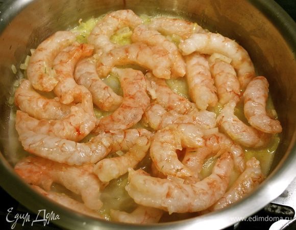 Как только лук посветлеет, добавить очищенные креветки. Обжаривать, помешивая...