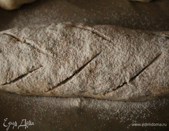 Сформовать из теста батон, хорошо присыпать сверху белой мукой и дать подойти 25-30 минут, затем сделать при помощи острого ножа сделать по 3 надреза с каждой стороны. Духовку нагреть до 180 градусов, сбрызнуть стенки холодной водой и посадить хлеб на противень. 