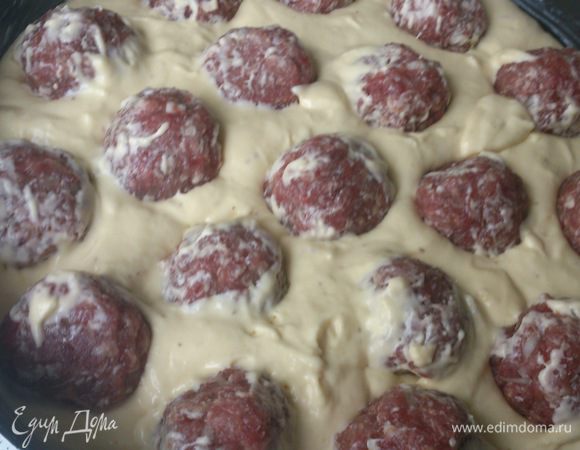Форму для выпечки смазать любым маслом. Вылить тесто и равномерно распределить по тесту фрикадельки.