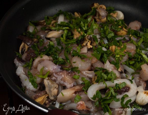 Разогреть масло в глубокой сковороде на среднем огне, положить чеснок и обжарить. Вынуть чеснок, когда он начнет менять цвет. Добавить морепродукты, петрушку.