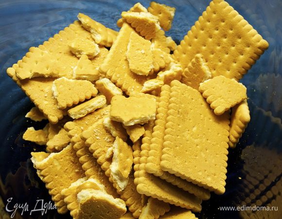 Приготовить и взвесить все ингредиенты. Сливочное масло заранее достать из холодильника, чтобы оно достигло комнатной температуры. 
Начнем с приготовления белой шоколадной массы. Печенье положить в миску и измельчить руками не очень мелко. 