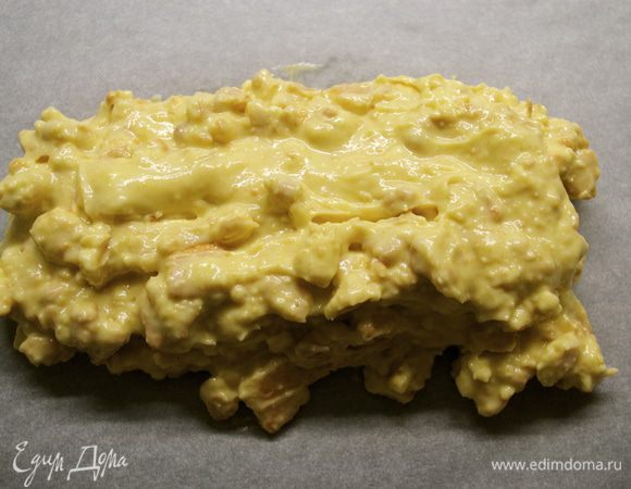 Отрезать лист пекарской бумаги, положить перед собой и выложить в центр полученную белую шоколадную массу. Сформировать брусок длиной примерно 20 см.  