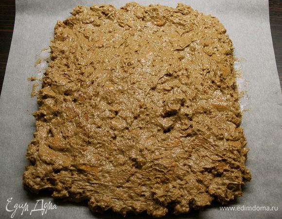 Добавить к шоколадной массе поломанное печенье и перемешать. Расположить перед собой лист пергаментной бумаги. Выложить на бумагу шоколадную массу и разровнять, придав ей форму прямоугольника, с учетом того, чтобы получилось в центре завернуть белую сердцевину.  