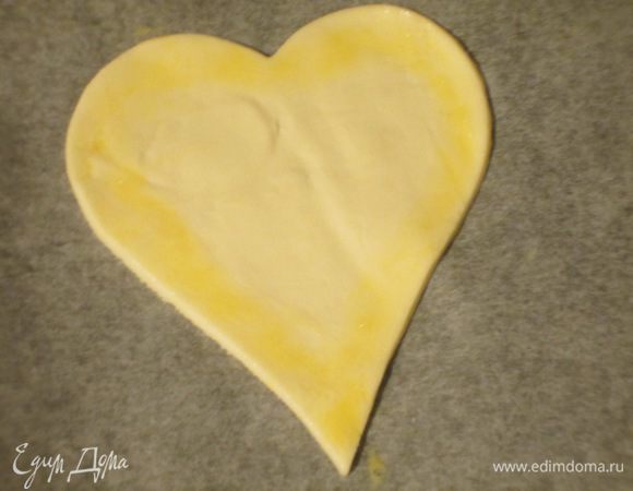 Цельные сердечки выложить на противень с пергаментом и смазать края взбитым яйцом.