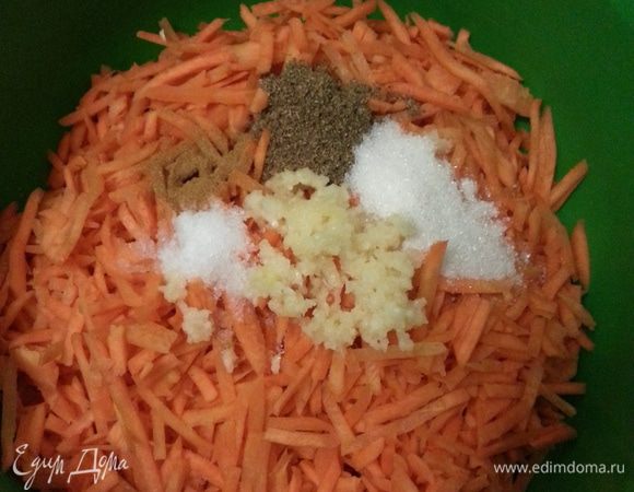 Натираем морковь на терке. Чеснок чистим, пропускаем через пресс, выкладываем на морковь, также выкладываем все специи...