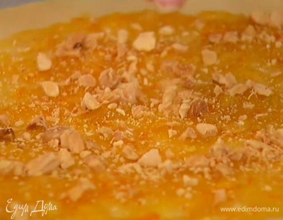 Половину теста раскатать в тонкий пласт и выложить на бумагу для выпечки, затем, отступая на 2 см от края пласта, смазать апельсиновым джемом и посыпать измельченными орехами.