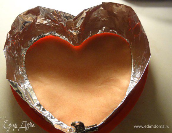 Достать бисквит. Вымыть форму. Вырезать из пекарской бумаги донышко формы. Стенки формы нарастить с помощью сложенной в несколько раз фольги. Скрепить концы ленты из фольги металлическим зажимом.
Если у вас форма достаточно большая, то можно и не наращивать ничего. Я это делала для того, чтобы увеличить высоту формы, она у меня совсем небольшая, а торт должен быть высоким.