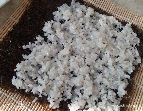 Приступаем к роллам. Наливаем в чашечку воды, для смачивания рук. Первый ролл делаю всегда самый простой: на шероховатую поверхность листа выкладываю рис, не доходя 3 см с верхнего края (это будет "замок").