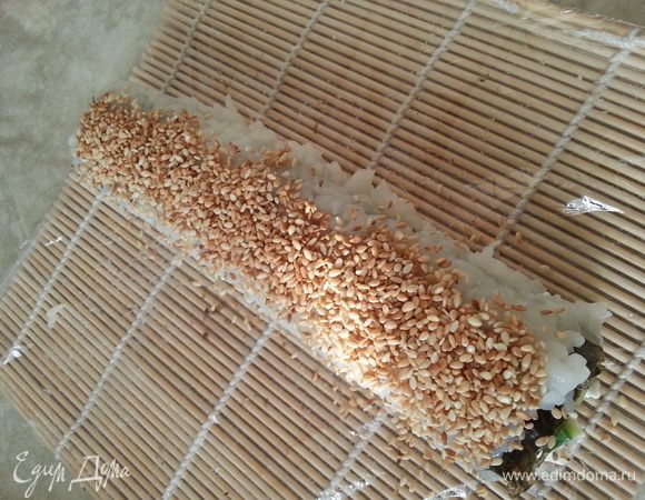 С помощью коврика сворачиваем. На каждую сторону посыпаем кунжут, придавливаем руками через коврик.