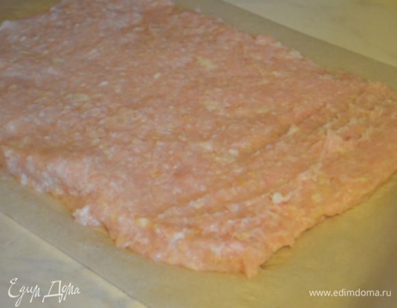 На столе расстелить большой пергаментный лист, смазать его маслом и выложить на него фарш в форме прямоугольника примерно 20х35 см.