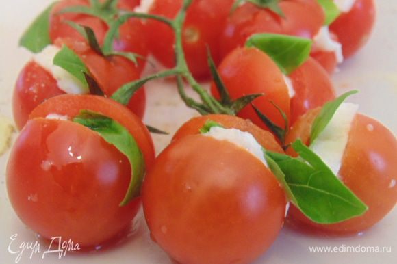 На помидорках сделать надрезы, вставить кусочек моцареллы и листик базилика. Сбрызнуть отливковым маслом, посолить и поперчить.