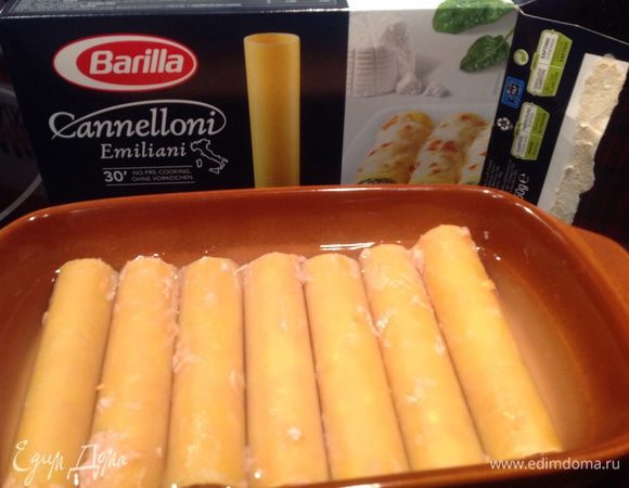Заправить каннеллони фаршем и положить в форму для запекания. Налить кипяток, так чтобы полностью покрывало водой, но не больше.