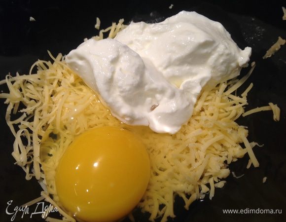 Сыр (можно использовать любой твердый сыр, у меня Российский) натереть, добавить яйцо и сметану, хорошо смешать.