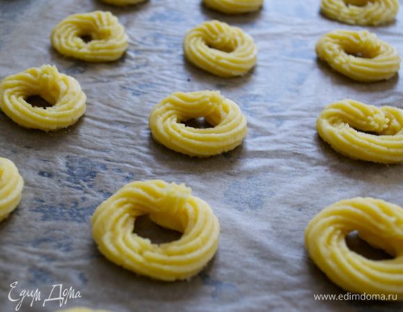 Противень смазать в нескольких местах маслом и накрыть листом пекарской бумаги. Печенье отсадить на противень в виде маленьких бубличков... 