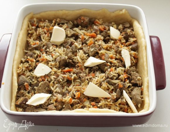 Тесто разделить на две неравные части. Раскатать, выложить в смазанную маслом форму, сделать бортики. Равномерно выложить начинку. Для сочности я добавила кусочки масла, можно сметану.