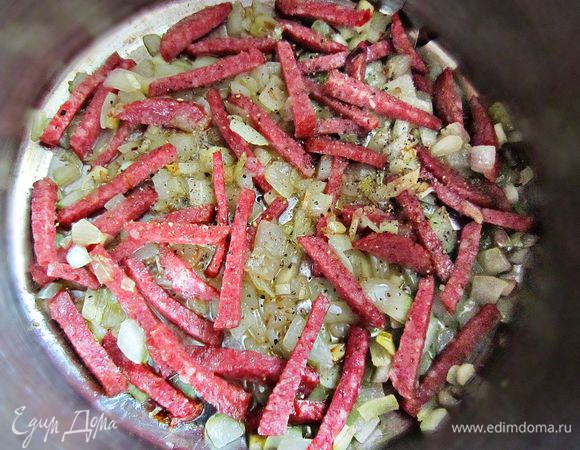 На оливковом масле слегка подрумянить лук и чеснок, добавить нарезанную колбасу и ещё обжарить всё вместе пару минут.