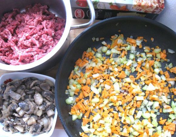 Лук порезать кубиками. Морковь порезать на мелкие кубики, стебель сельдерея порезать на небольшие кусочки. Пармезан натереть на крупной терке. Мясо прокрутить через мясорубку.Обжарить овощи – морковь, половину лука и сельдерей – на оливковом масле.