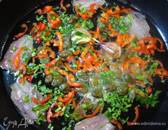 Вылить масло от тунца в сковороду. Отправить туда же чеснок, каперсы и анчоусы вместе с маслом.
Рубленые стебли петрушки и чили добавить в сковородку.
Готовить, помешивая, две минуты.
