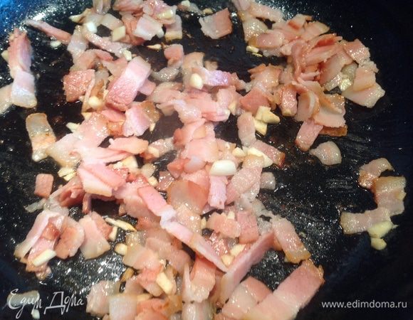Бекон нарезать, чеснок измельчить и обжарить на той же сковороде, где готовились овощи.