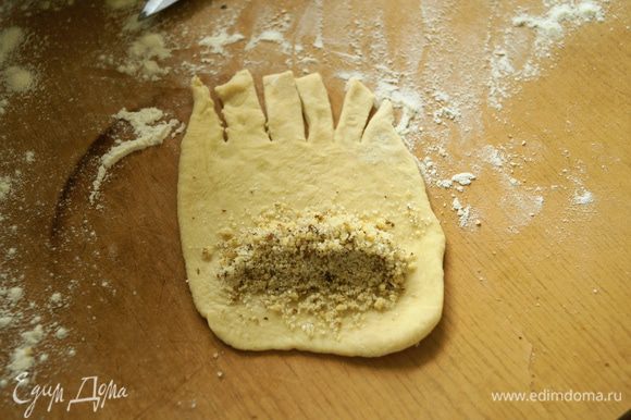 Разделить тесто на части. Взять одну часть и раскатать овальную лепешечку, на один край положить начинку из грецких орехов, другой край нарезать полосками.