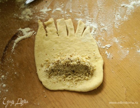 Разделить тесто на части. Взять одну часть и раскатать овальную лепешечку, на один край положить начинку из грецких орехов, другой край нарезать полосками.