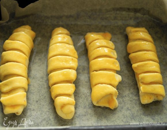Выложить булочки на противень застеленный пергаментом и смазанный маслом, смазать булочки взбитым желтком.