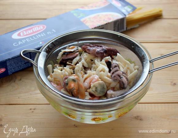 С морского коктейля из ассорти морепродуктов слейте лишнее масло.