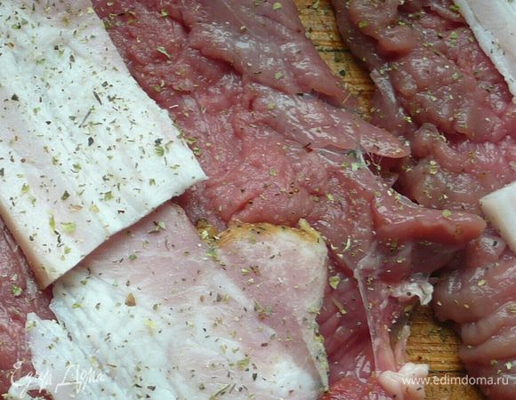 Мясо нарезать на шесть кусочков по 70 г каждый. Хорошо отбить (отбить можно скалкой, в этом случае структура волокон не разрушается  мясо остается более сочным). На каждый кусок положите  итальянские травы, измельченный чеснок, соль, перец, кусочек бекона.