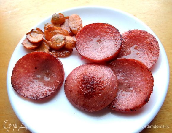 Колбасу и морковь зажариваем до румяного состояния, вынимаем на блюдце. Колбаса отдаст свой жир.