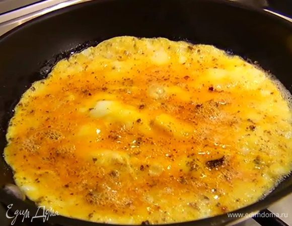 Разогреть в сковороде сливочное и оливковое масло, влить яйца со специями и готовить омлет в течение 2 минут.