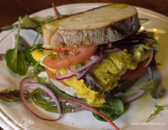 Хлеб сбрызнуть оставшимся маслом Extra Virgin, выложить на оба куска кружки помидора и лук. На один кусок хлеба поместить листья салата, а на другой выложить омлет, затем сложить их вместе.