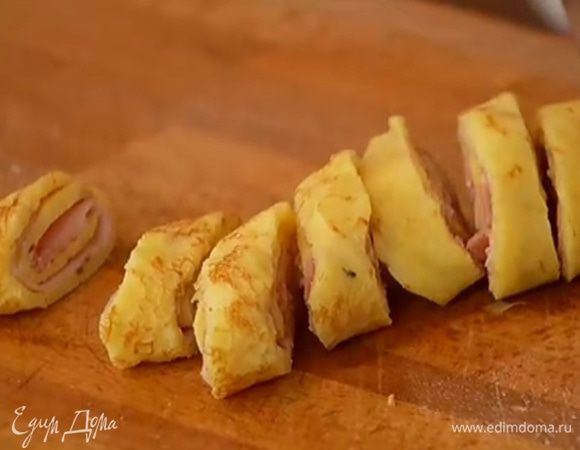 На несколько блинов выложить буженину, свернуть рулетом, нарезать наискосок небольшими кусочками и скрепить зубочистками.