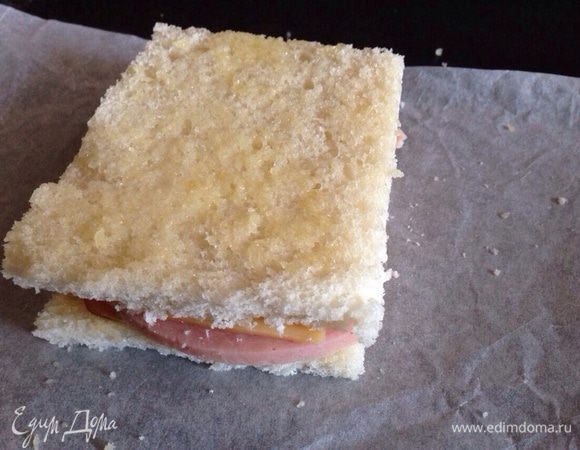 Накрыть оставшимся ломтиком хлеба, смазать сливочным маслом. И отправить запекаться в духовку на 5 минут, при температуре 180 градусов. Затем перевернуть и поставить еще на 5 минут в духовку.