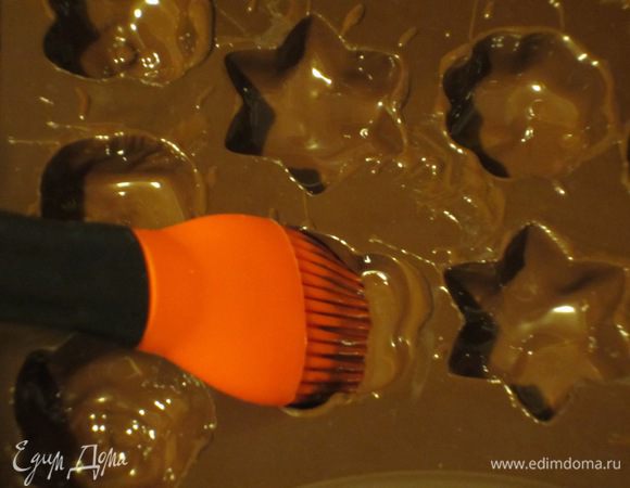 100 г шоколада отложить для начинки,а оставшейся шоколад при помощи кисточки нанести на стенки и дно формочек. Отправить форму в морозильную камеру, чтобы шоколад застыл. Затем нанести ещё один слой шоколада и снова отправить в морозильную камеру.