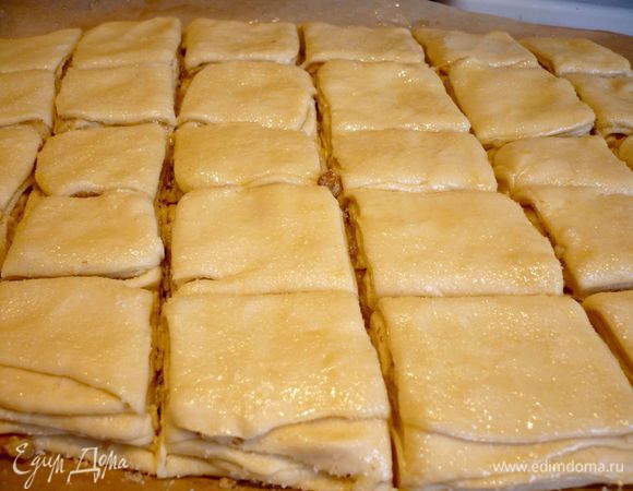 То же самое проделываем с остальными частями теста и начинкой, выкладывая каждый последующий пласт теста на предыдущий, не забываем при этом смазывать каждый пласт маслом и присыпать начинкой. Затем переносим нашу прямоугольную конструкцию прямо на бумаге на доску и острым ножом разрезаем ее на квадратики. 