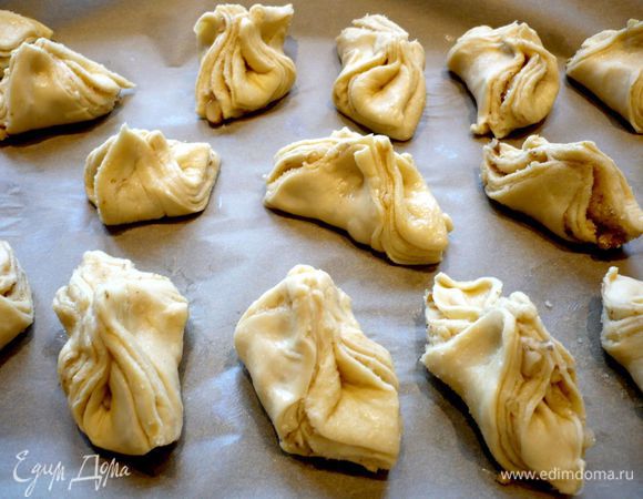 На противень снова кладем пергаментную бумагу и начинаем формировать пирожки. Скрепляем у каждого квадратика противоположные уголки, но не вершины уголков, а отступая от вершин слегка. Выкладываем пирожки на пергамент. Ставим в духовку на 20 минут. 