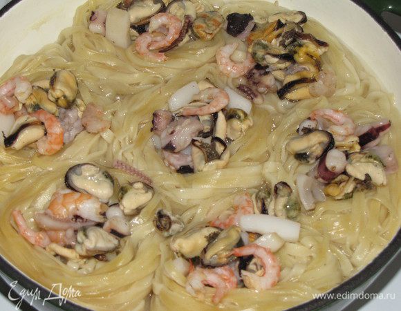 Накрыть гнезда тарелкой подходящего диаметра и аккуратно слить из сковороды воду. Разложить по гнездам морской коктейль.