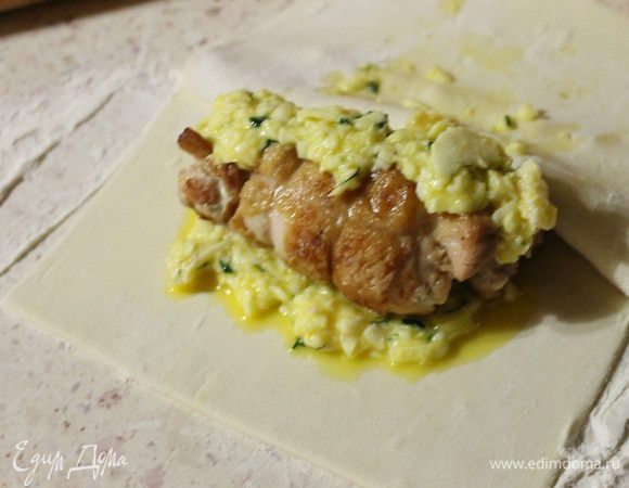 На тесто кладем смесь из сыра и яйца, потом куриный рулет, сверху и по бокам опять сыр, и накрываем квадратом теста. Хорошо защипываем края, смазываем молоком, сверху делаем три прокола ножом, чтобы был выход для пара и тесто не порвалось во время выпечки. Выпекаем в заранее разогретой духовке 20-30 минут, до красивого зарумянивания.